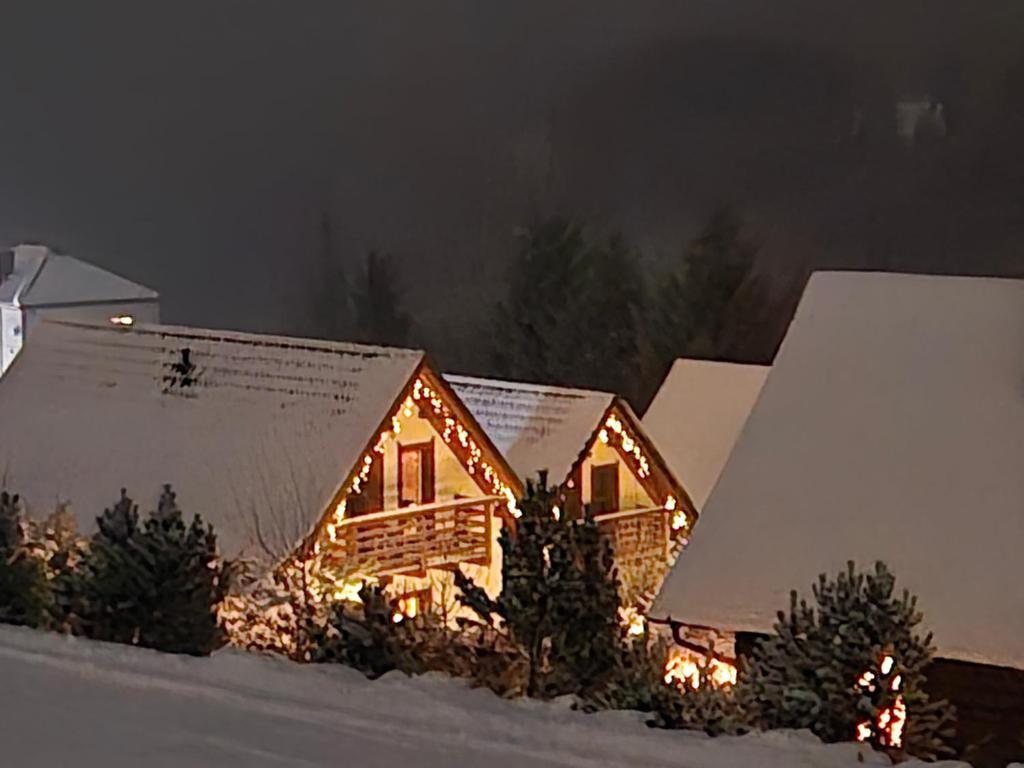 a log cabin with christmas lights in the snow at Domek u Małysza in Istebna