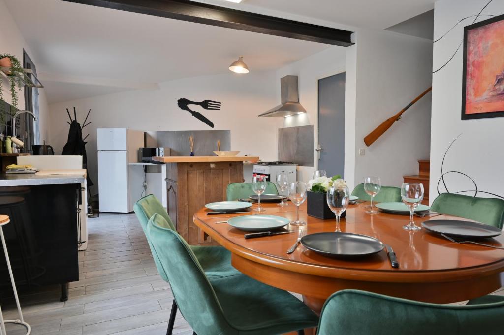a dining room with a wooden table and green chairs at La Champtocette de la Loire in Champtoceaux