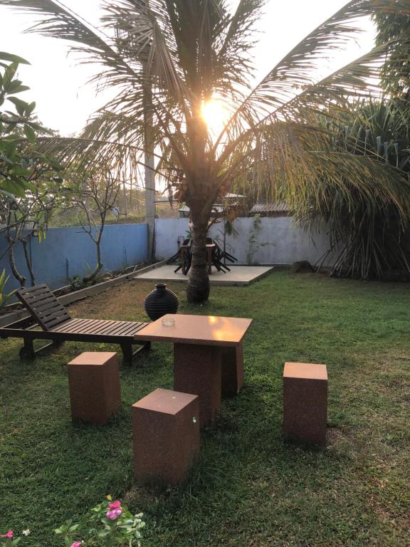 a table and benches in a yard with a palm tree at Luna Kuru Wild in Tangalle
