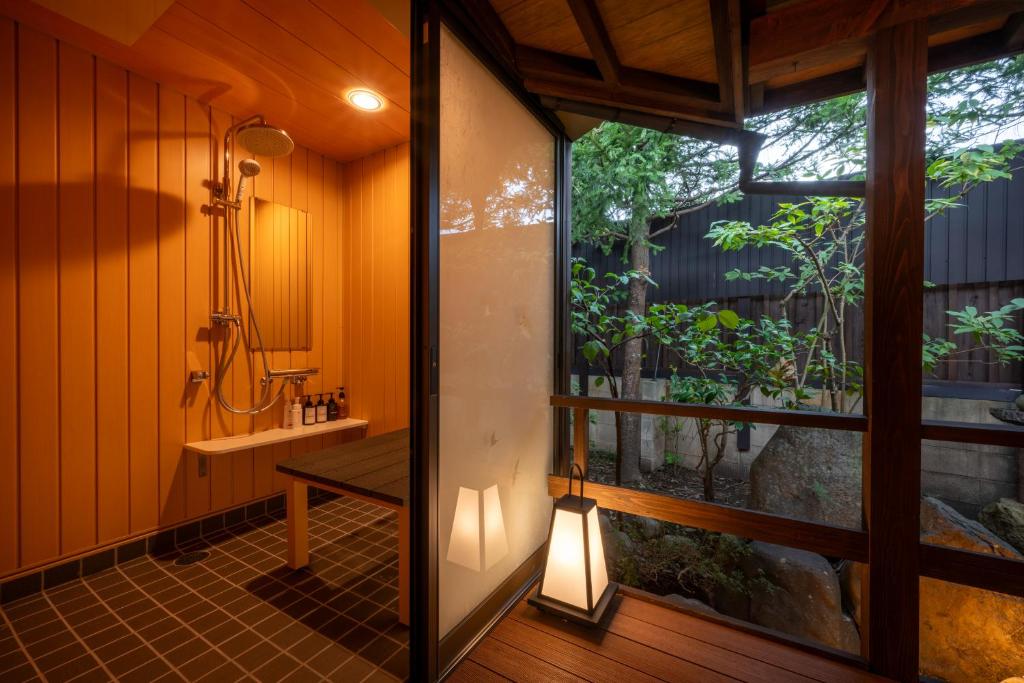 une salle de bain avec une douche et un lavabo et une fenêtre dans l'établissement Hohoemino Kuyufu Tsuruya, à Tendō