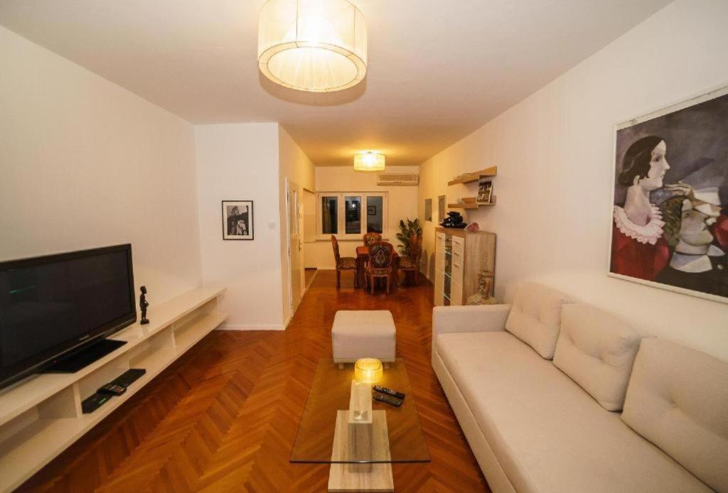 a living room with a white couch and a flat screen tv at Spacious beach apartment in Razvala