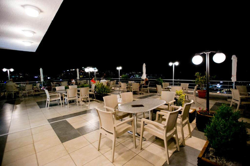 a restaurant with tables and chairs on a balcony at night at Oceanis Hotel in Kavála