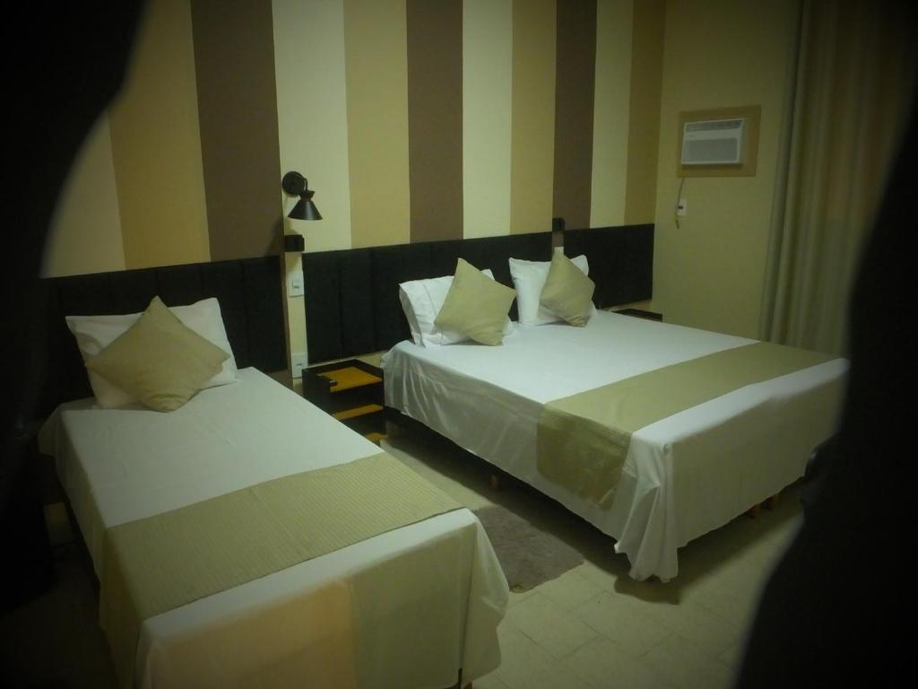 two beds in a hotel room at Hotel San Remo in Ubá