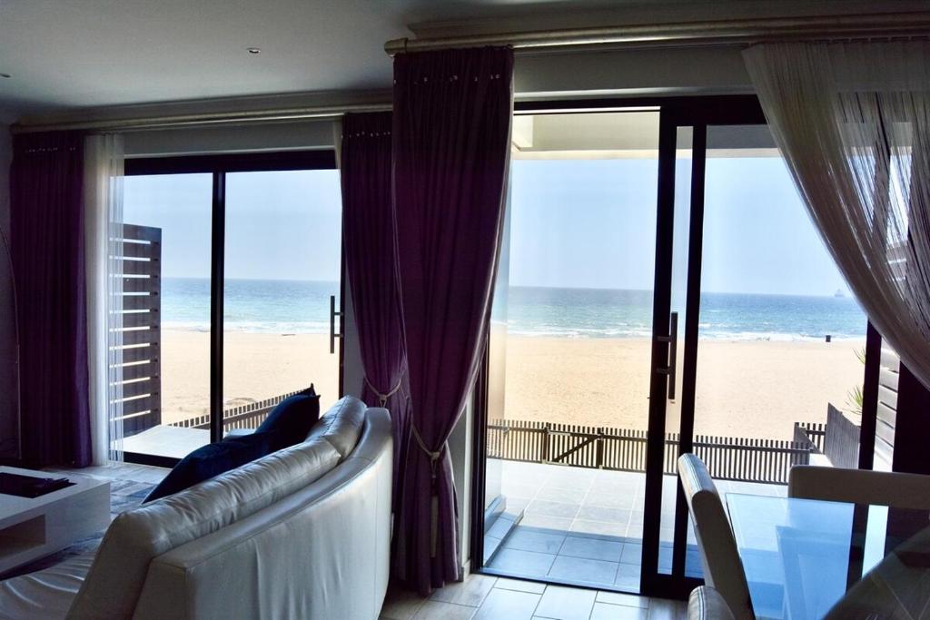 a living room with a couch and a view of the beach at Foreshore 2 Sea View Holiday accommodation in Langstrand