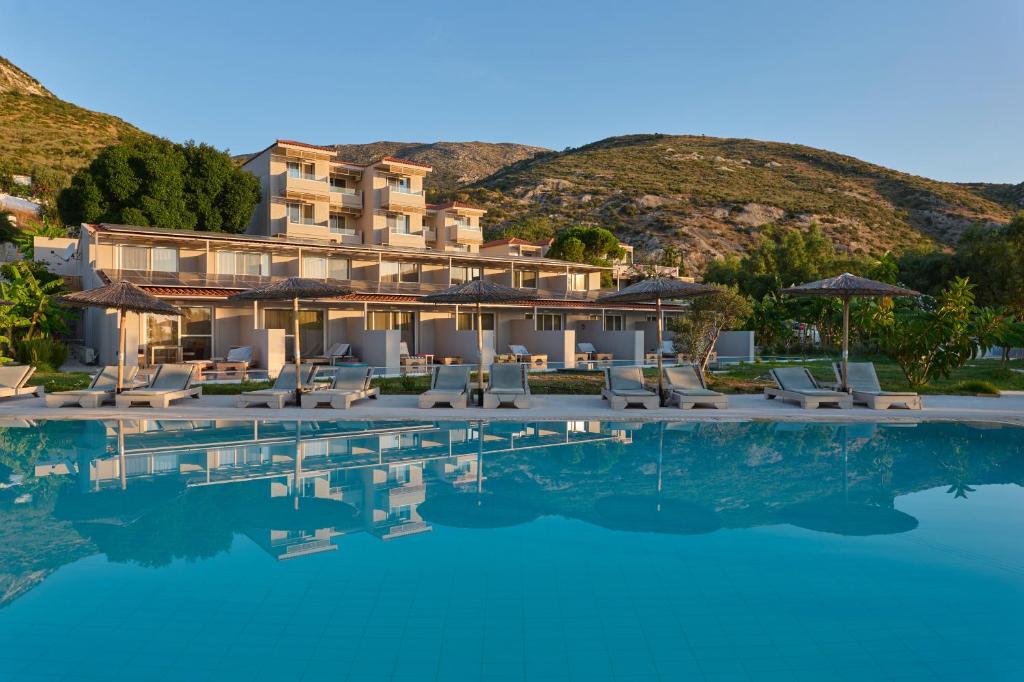 a resort with a swimming pool and chairs and a mountain at Pacifae Hotel in Katelios