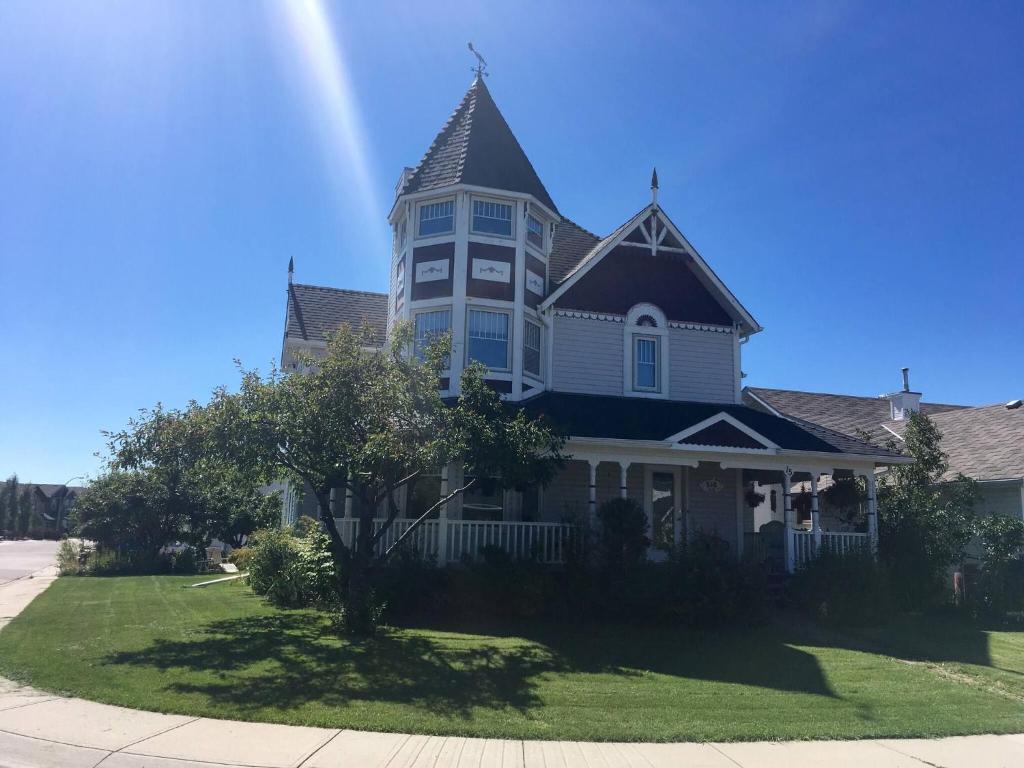 a large house with a turret on a lawn at Charming Victorian Home in Okotoks Elegant Comfort Modern Convenience in Okotoks