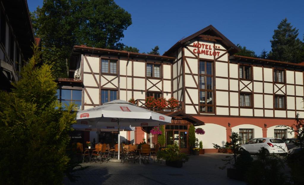 a building with an umbrella in front of it at Hotel Camelot in Szczawno-Zdrój