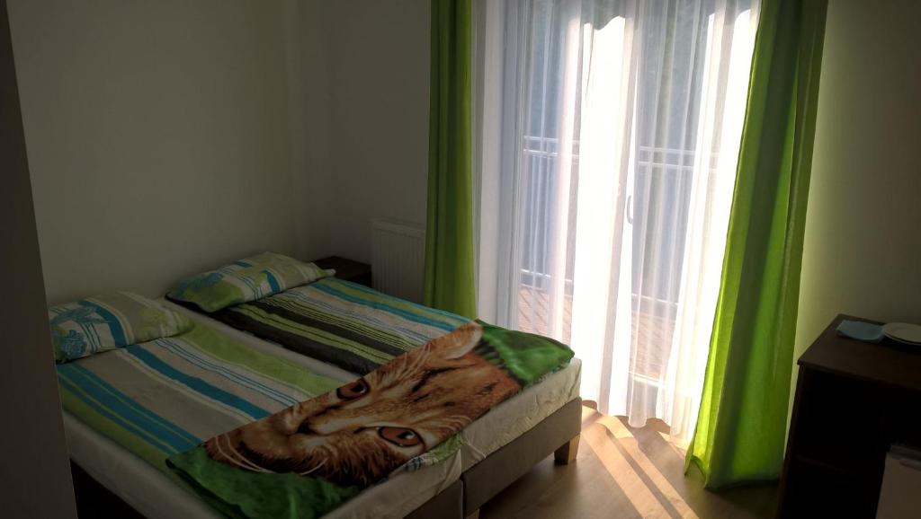 ein Schlafzimmer mit einem Bett mit einer Katze auf den Laken in der Unterkunft AQUILA Pokoje Gościnne in Mielno