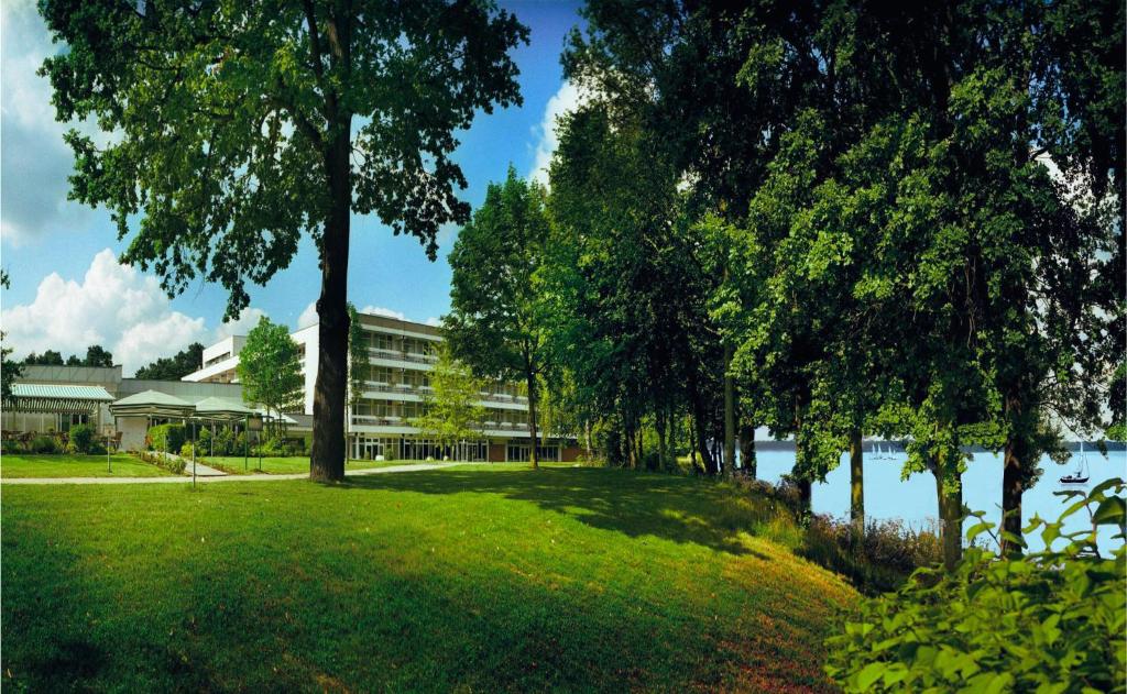 a park with trees and a building next to a lake at Müggelseeperle in Berlin