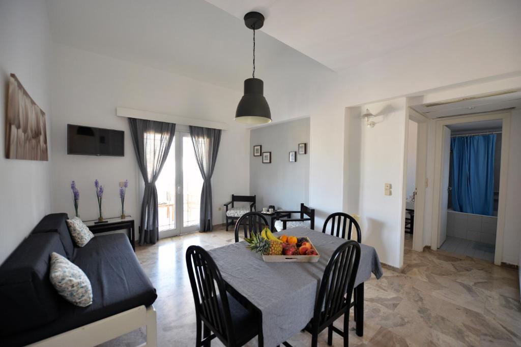 a dining room and living room with a table and a couch at Hotel Anna Apartments in Kokkíni Khánion