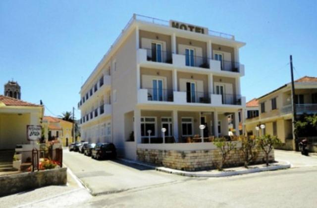 a large white building with cars parked in front of it at Mentor Hotel in Vathi