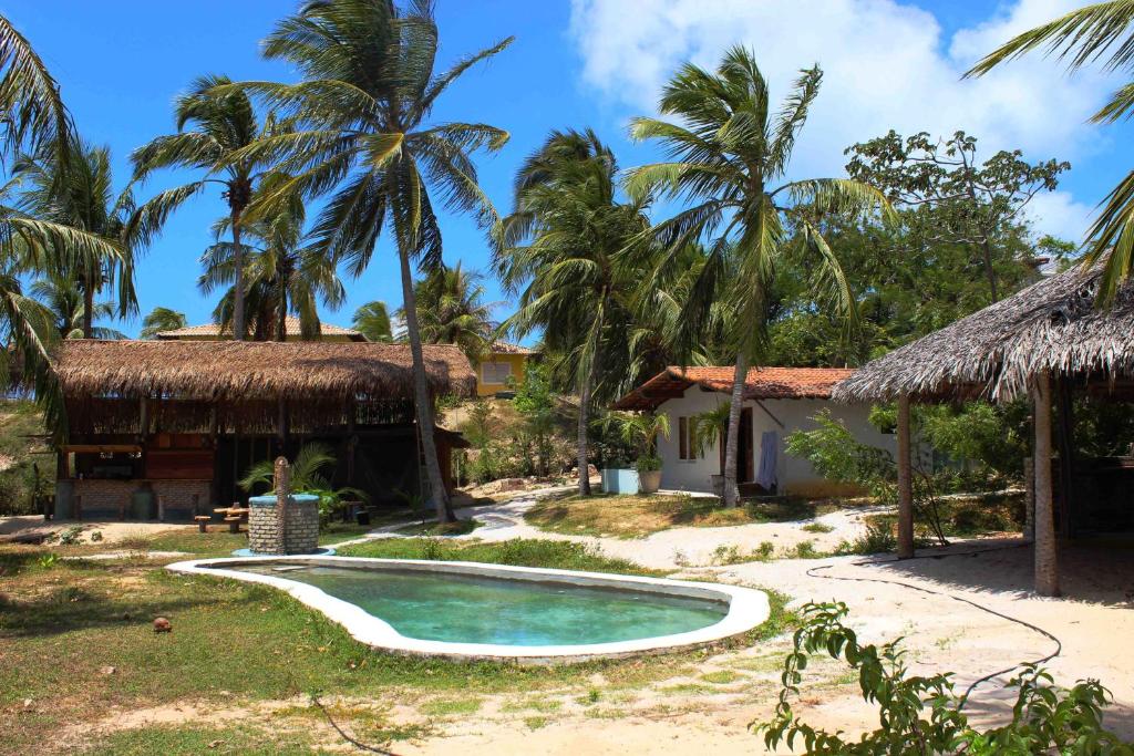 uma piscina em frente a uma casa com palmeiras em Lagoa dos Coqueiros em Maracajaú