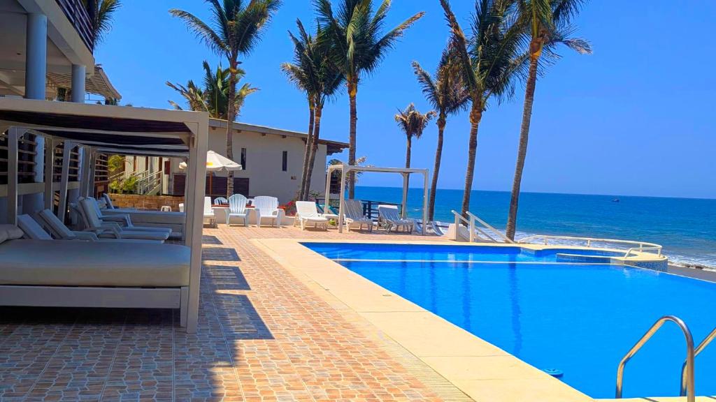 a resort swimming pool with the ocean in the background at Hotel Punta del Mar in Máncora Chico