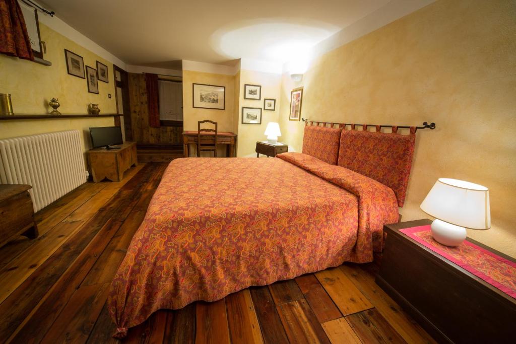 ein Hotelzimmer mit einem Bett mit einer orangefarbenen Tagesdecke in der Unterkunft B&B Al Nabuisson in Aosta