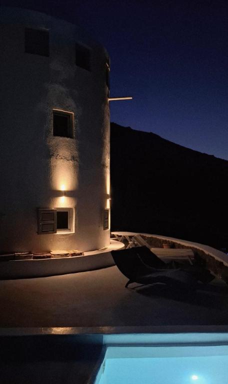 a building at night next to a swimming pool at Anemos Mill House in Imerovigli