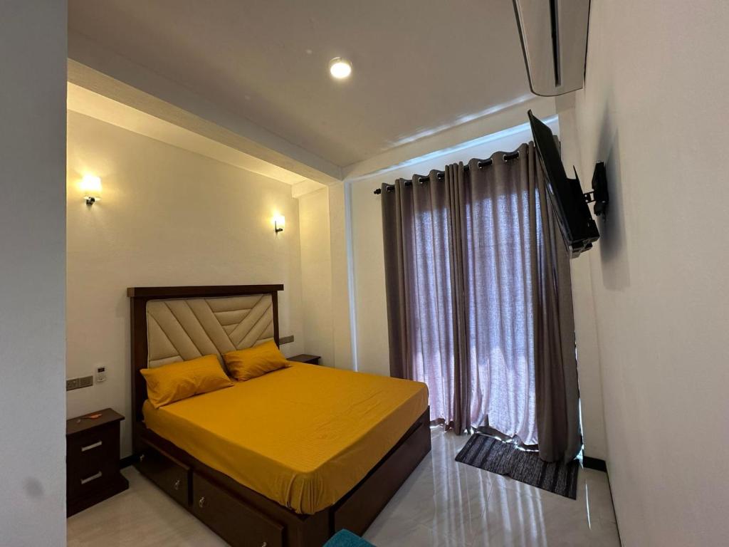 a bedroom with a bed with yellow sheets and a window at Andrew Transit Villa - Near Airport in Katunayaka