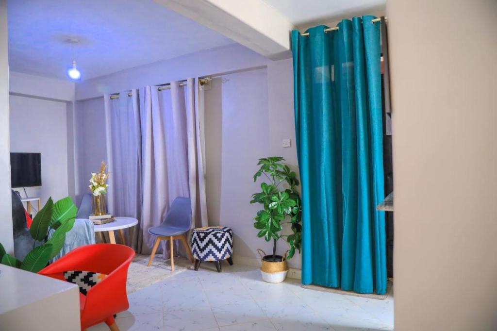a living room with blue curtains and a table and chairs at Bethany Cushy Home Ltd in Kisii