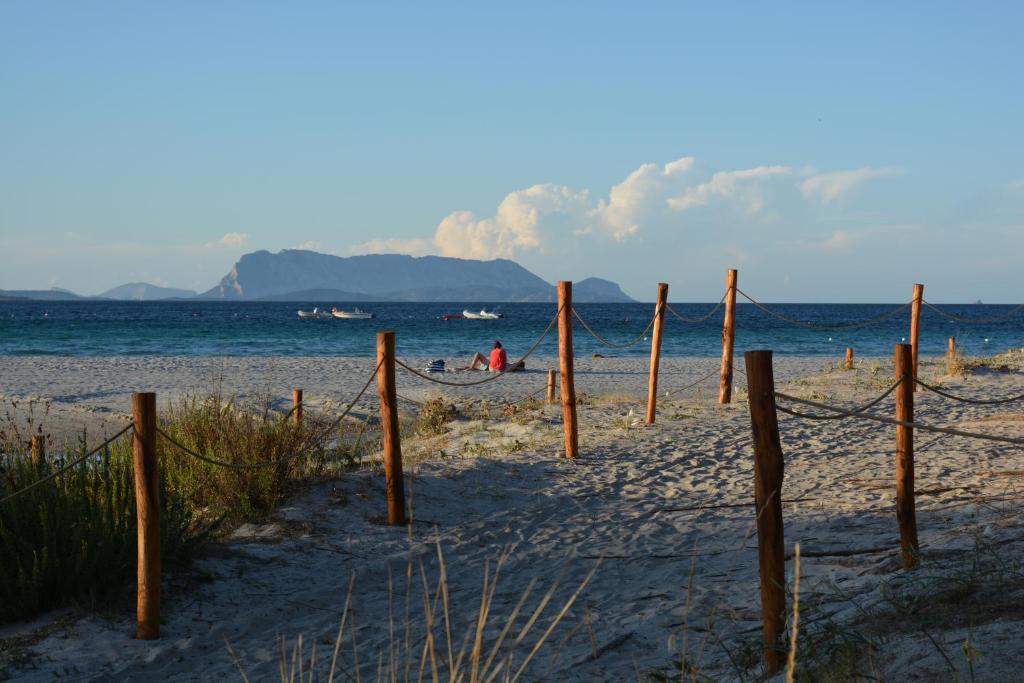 une plage avec une clôture sur le sable et l'océan dans l'établissement Residence L'Ulivo, à Budoni