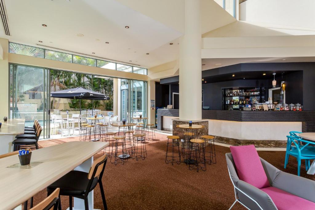 a restaurant with tables and chairs and a bar at Mantra Legends Hotel in Gold Coast