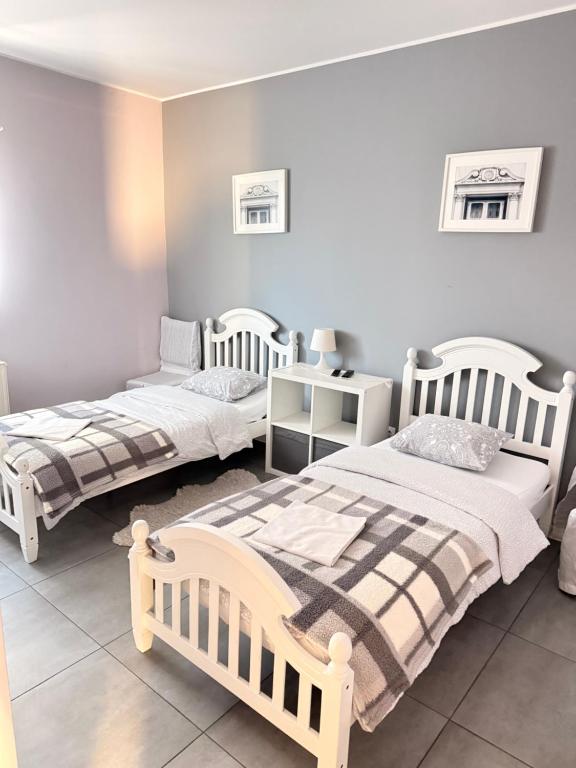 a bedroom with two beds and a table with a night stand at Noclegi Adriana Kacperska in Tuszyn