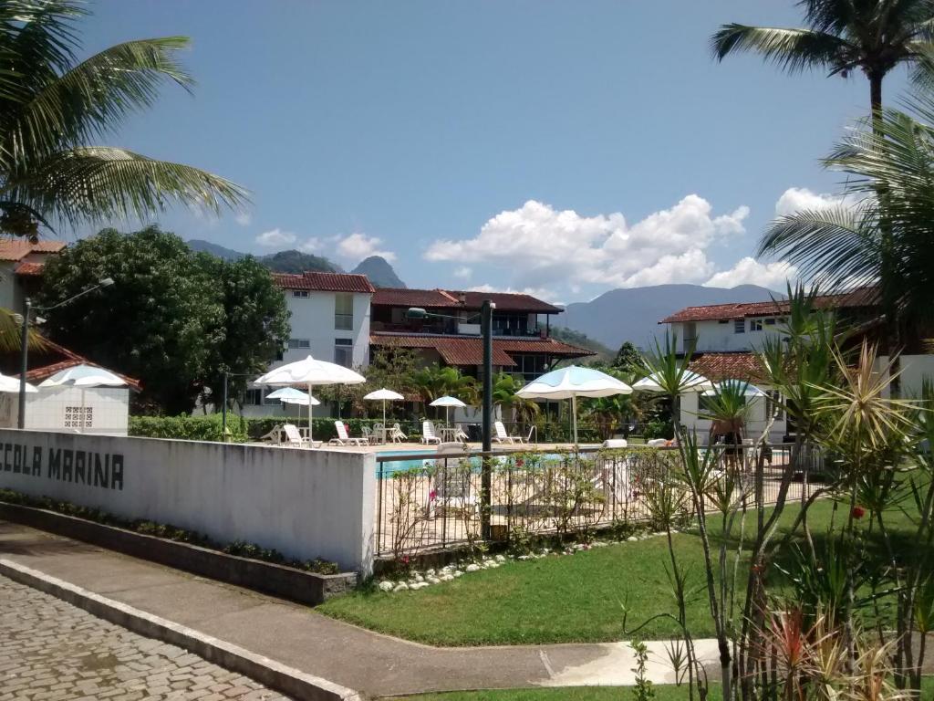 a resort with a pool and tables and umbrellas at Apartamento Piccola Marina BR Marinas Angra dos Reis Bracuí in Angra dos Reis