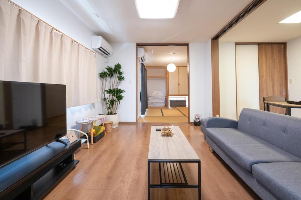 a living room with a blue couch and a tv at お宿 春Haru in Muromoto