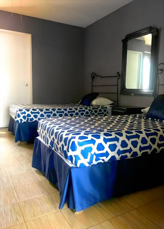 a bedroom with two beds with blue and white sheets at Casa Zapopan Hotel in Guadalajara