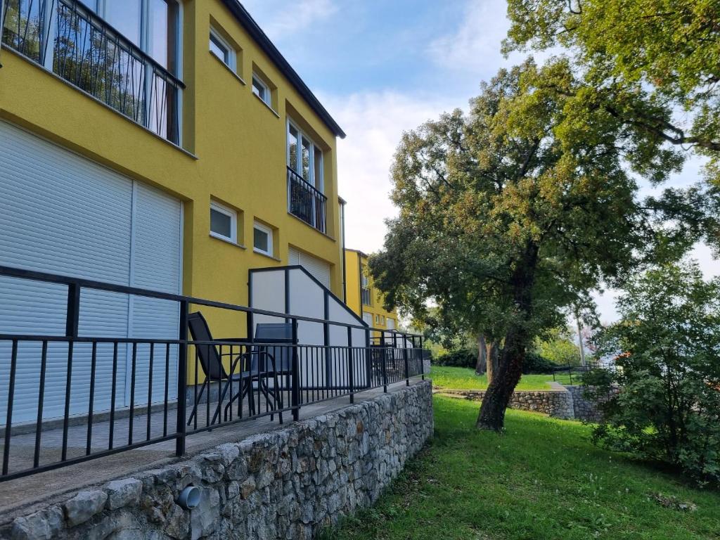 a yellow building with a bench next to a tree at Guest House Morska Grota in Povile