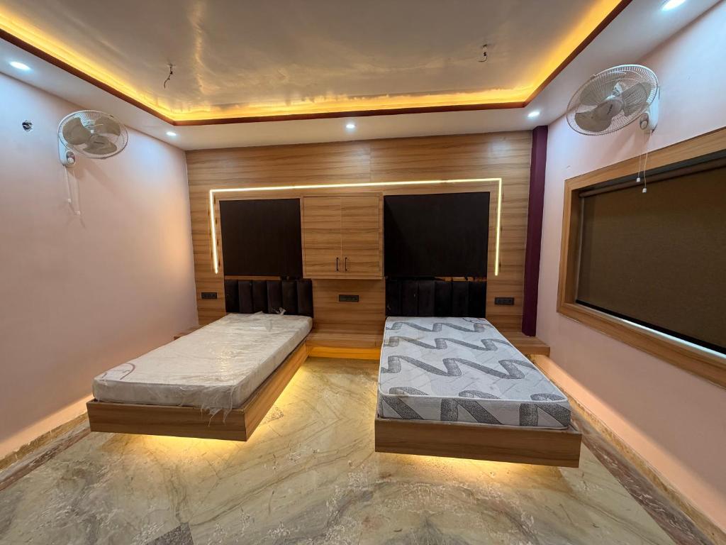 a bedroom with two beds and a flat screen tv at Govindam Palace in Govardhan