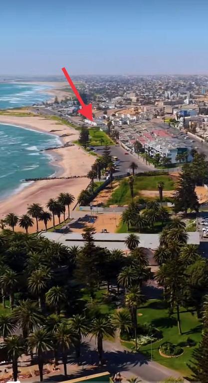 a red arrow points to a beach with palm trees at Sleep to the Sound of Waves - Full Private Apartment in Swakopmund