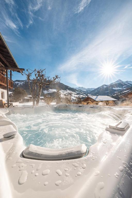 a hot tub covered in snow with the sun in the background at Hunters Lodge Chalet Superior in Alpbach