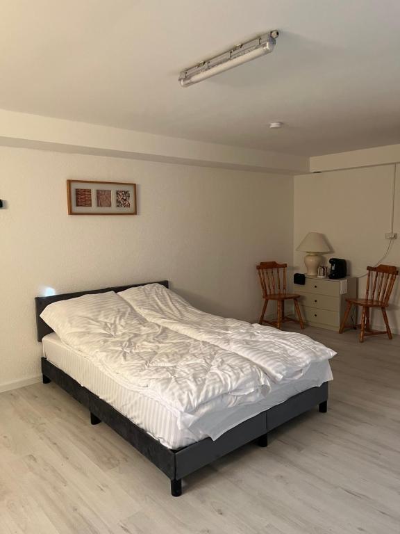 a bedroom with a bed in a room with two chairs at Ferienwohnung Fatlume No 1 in Bad Honnef am Rhein