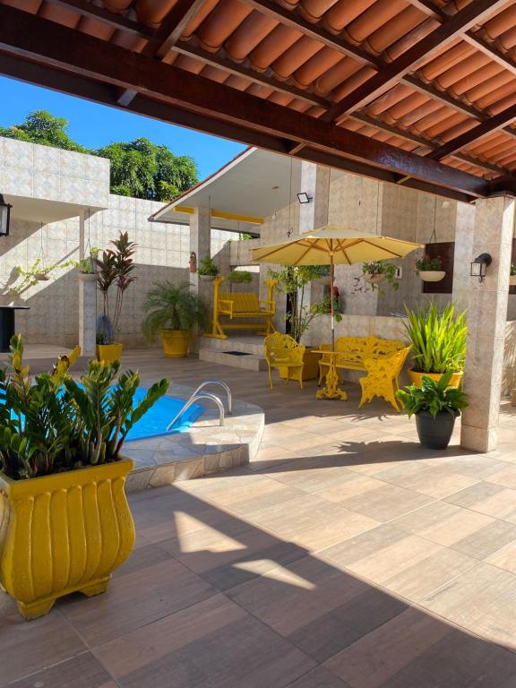 a patio with yellow chairs and an umbrella at Casa Porto in Porto De Galinhas
