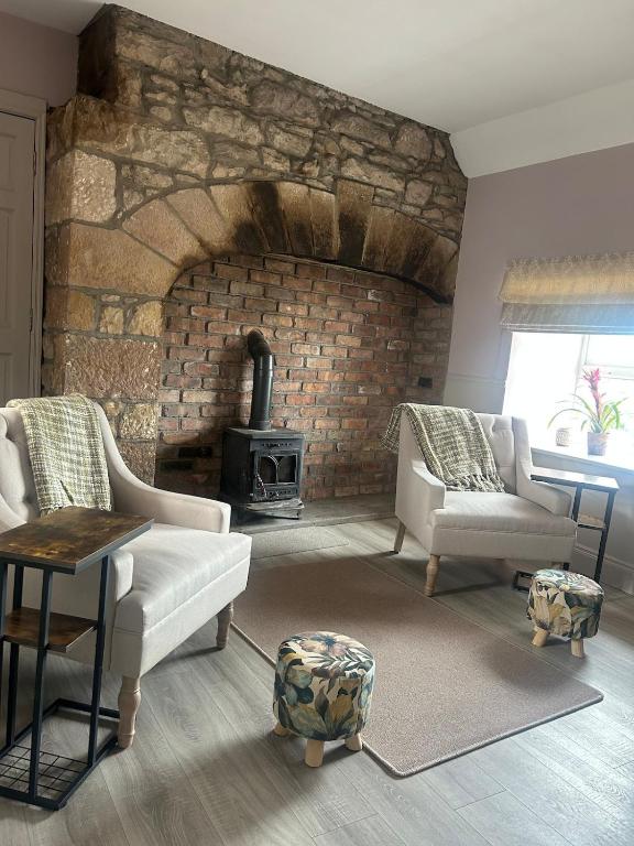 a living room with a stone fireplace with two chairs and a table at Clontrain Cottage in Carrickmacross