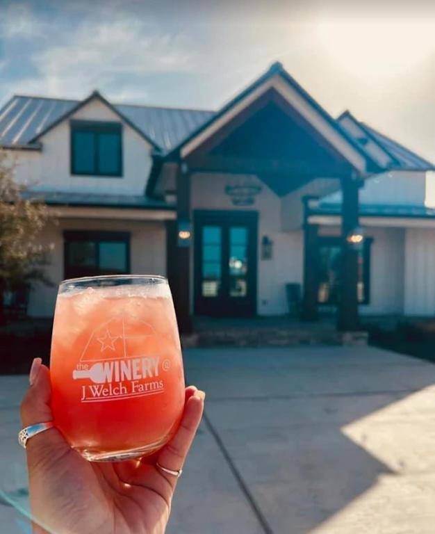 a person holding a glass of beer in front of a house at Starry Skies RV in Victoria