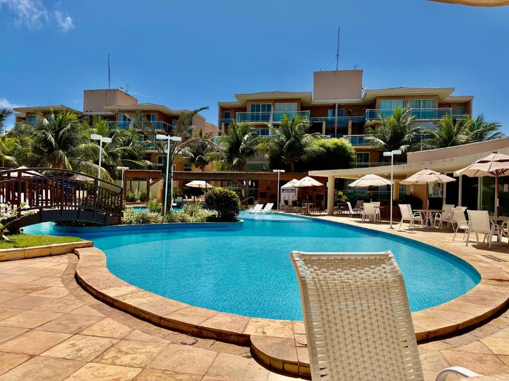 a swimming pool with a chair and a building at Palm Beach Residence in Aquiraz