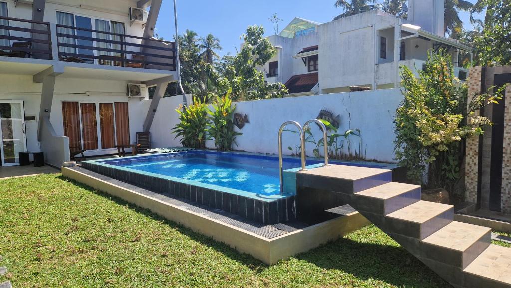 a swimming pool in a yard next to a house at Jkl MahaOya Villa in Wayikkal