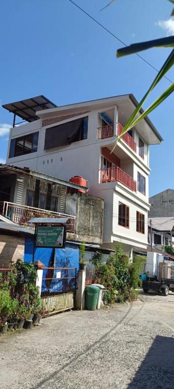 a large white building with a balcony and a street at Toraja Hikari Homestay in Rantepao