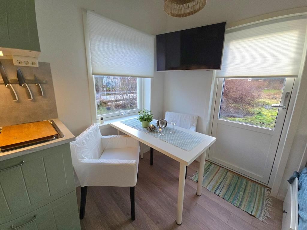 a kitchen with a white table and two windows at Nybyggd loftstuga i centrala Grebbestad in Grebbestad
