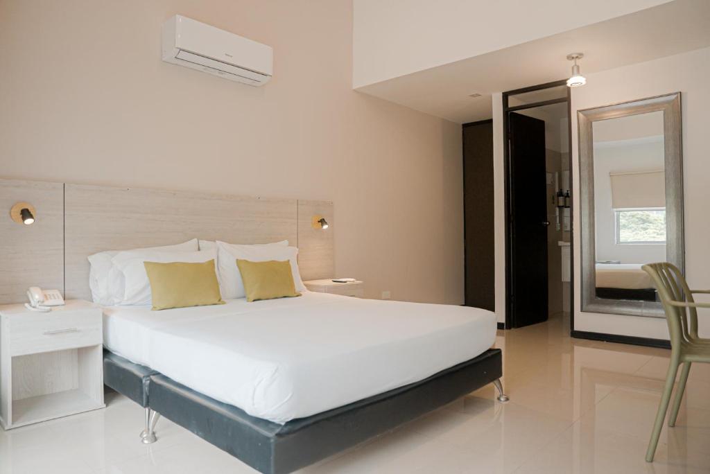a bedroom with a large white bed and a mirror at Basic Hotel Chipichape by Hoteles MS in Cali