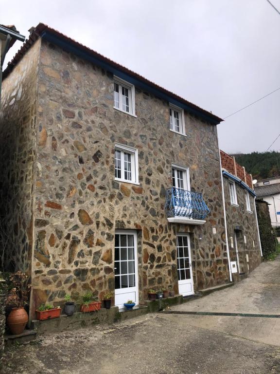 an old stone house with a balcony on a street at Casa da Carvalha - Ádela in Açor