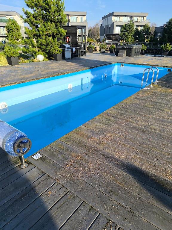 a blue swimming pool on a wooden deck at Fly & Pool Apartment in Palanga