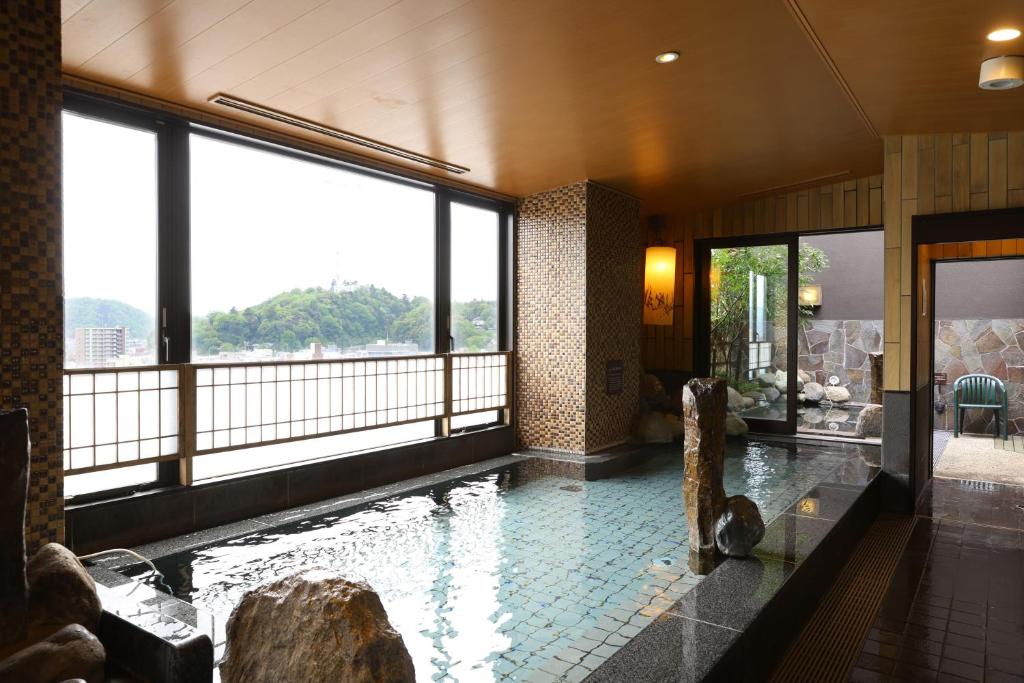 a swimming pool in a building with a large window at Dormy Inn Premium Fukui Natural Hot Spring in Fukui