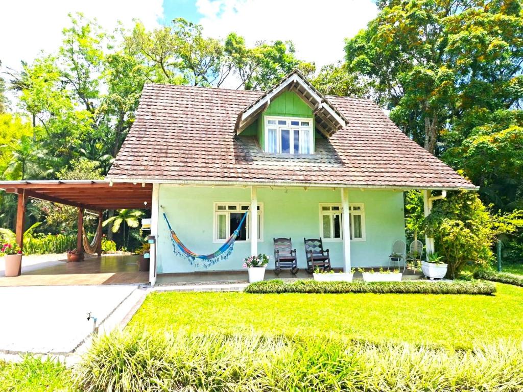 a small house with a hammock in the yard at Recanto Hellmann in Gaspar