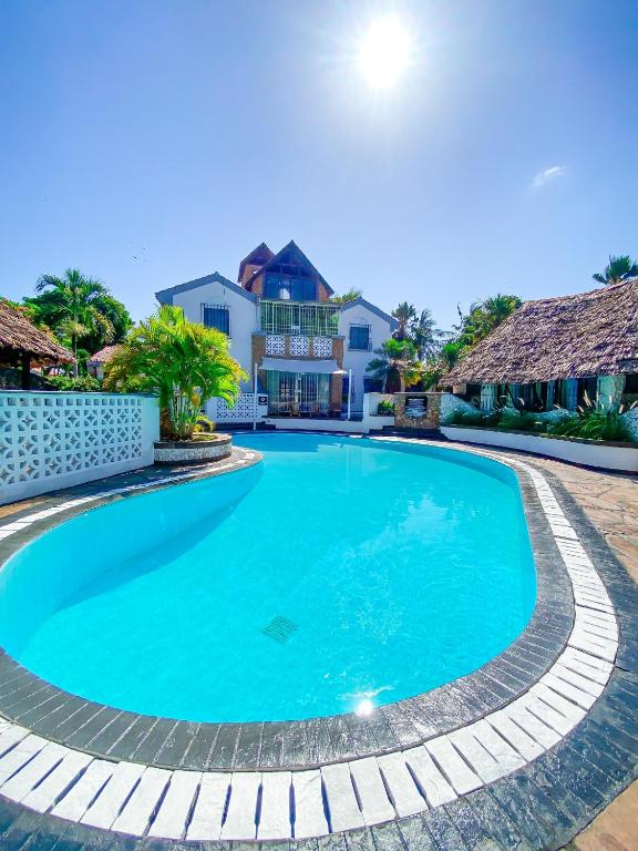 a swimming pool in a villa with a house in the background at 9 bedroom Villa in Mombasa