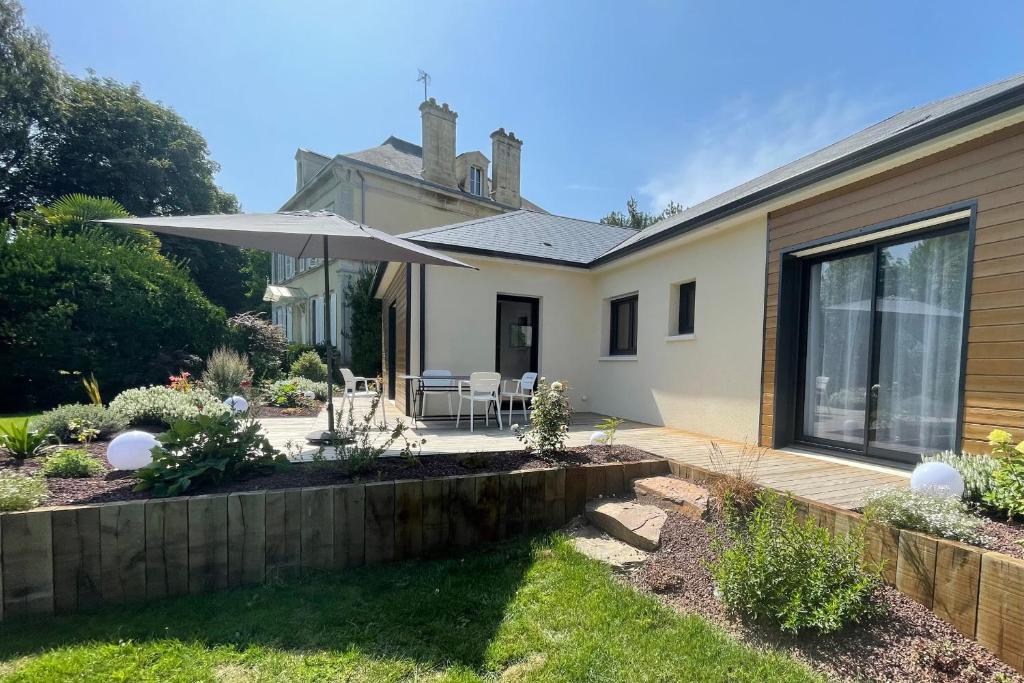 a house with a patio with an umbrella at Le Clos des Marmuzots parking & garden in Bayeux