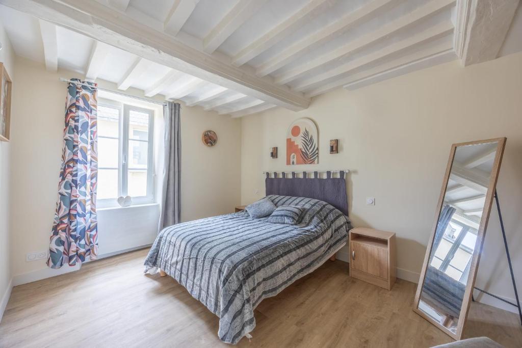 a bedroom with a bed and a window and a mirror at Les Colibris little house in the city-center in Arromanches-les-Bains