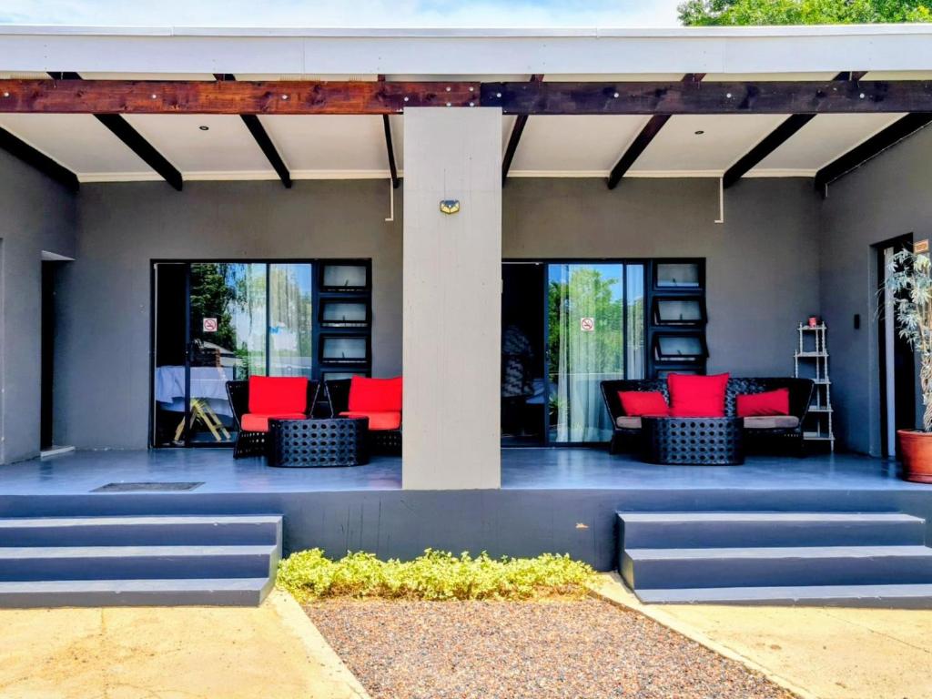 a patio with red chairs on a house at Kaleaba House on the Riverside in Parys