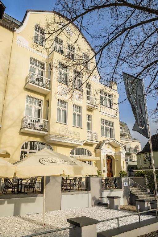 a building with tables and umbrellas in front of it at Hotel Alex an der Ahr in Bad Neuenahr-Ahrweiler