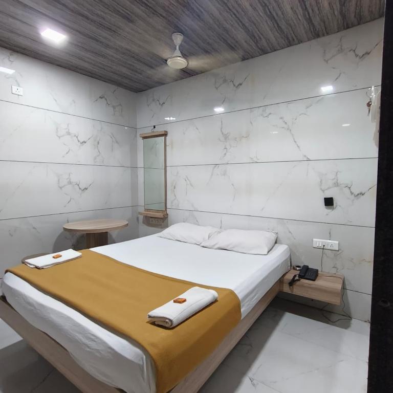 a bedroom with a large bed with white walls at Sai Lodging And Boarding in Dombivli